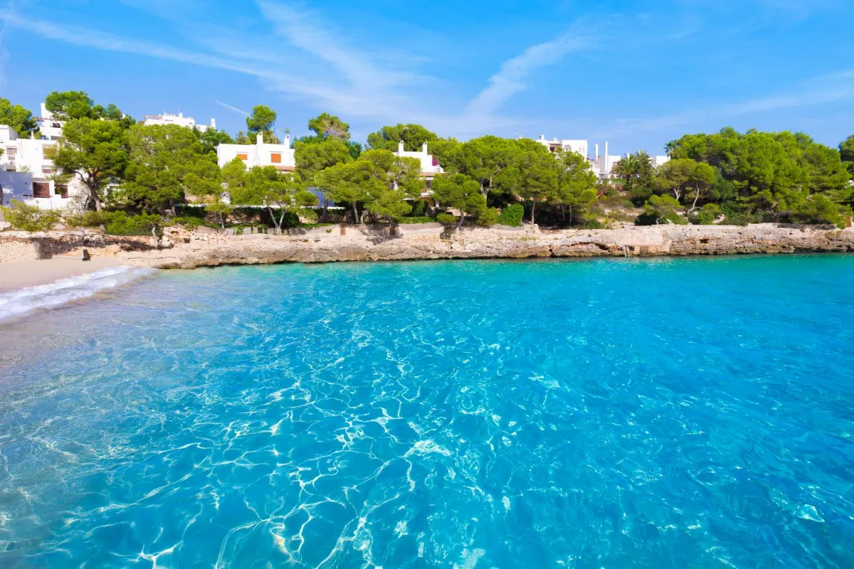 Strand med hoteller i baggrunden i byen Cala d'Or på øen Mallorca i Spanien.