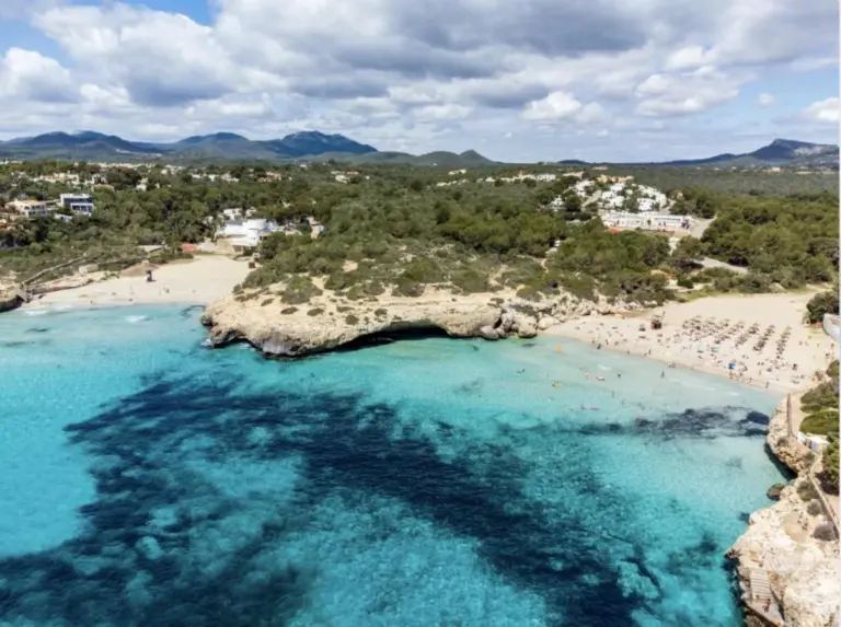 Klart lavt vand ved strand i byen Calas de Mallorca på Middelhavsøen Mallorca i Spanien.