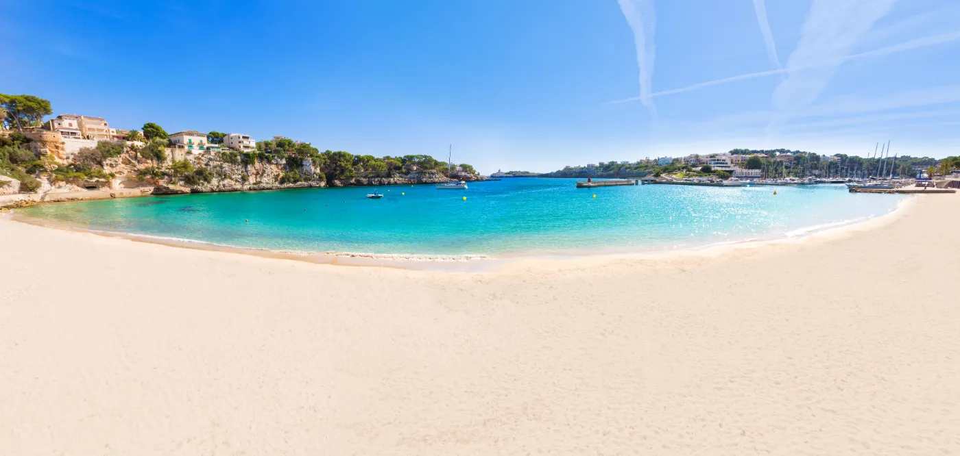 Sol over strand i byen Porto Cristo en sommer, på ferieøen Mallorca i Spanien.